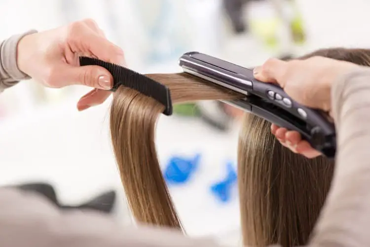Girl using a straightening iron to straight her hair