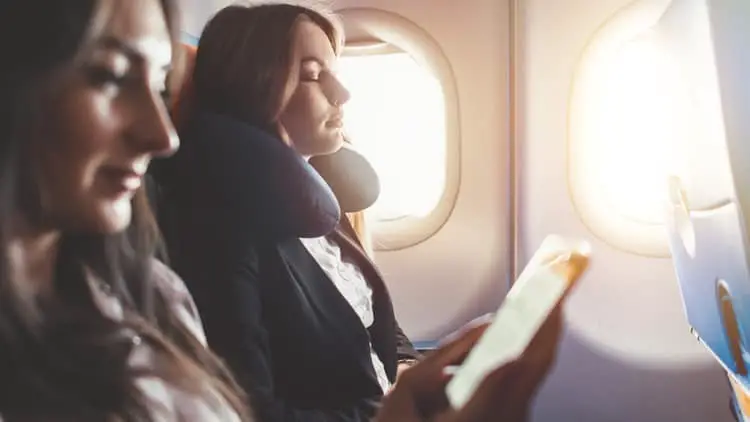 Girl reading a book on an airplane on why skin breaks out when flying on an airplane