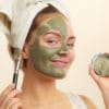 Girl applying clay mask to her face to get rid of oil on her nose and forehead